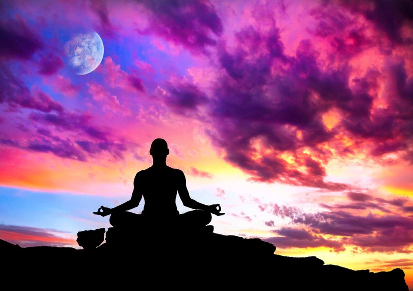 Yoga meditation in lotus pose by man silhouette with moon and purple dramatic sunset sky background.