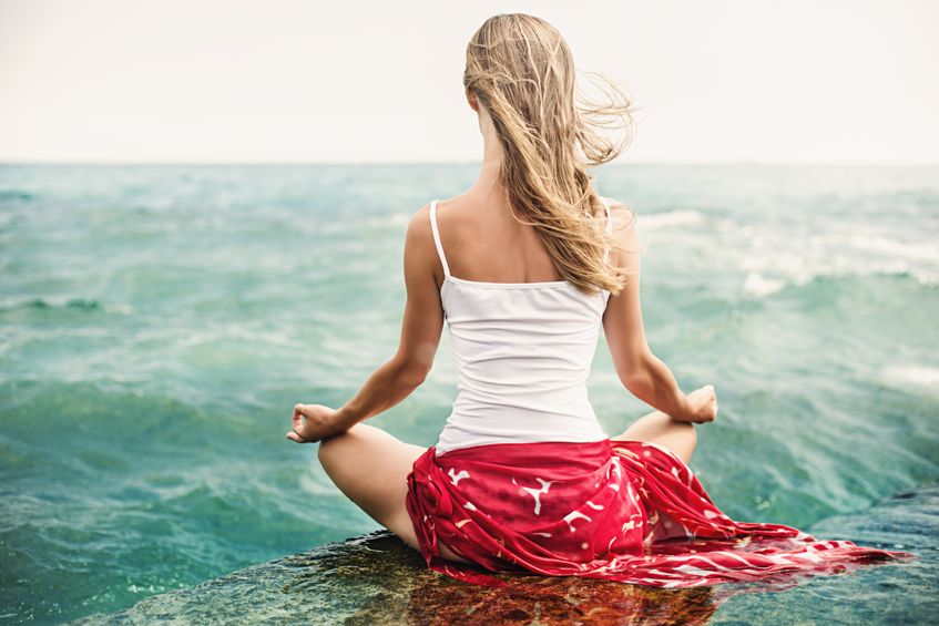 Blond woman meditating on the beach