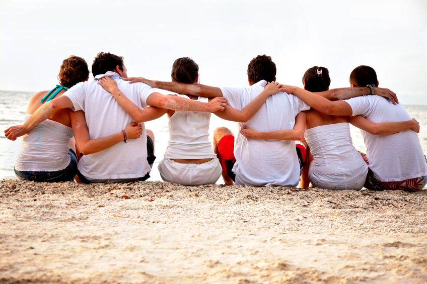 Group of friends hugging at the beach
