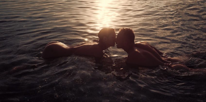 Couple in love swim naked in ocean water