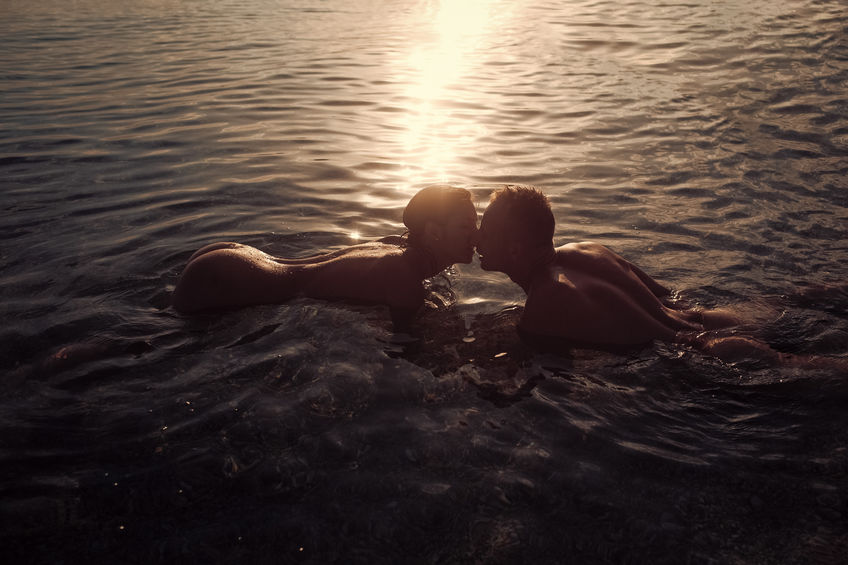 Couple in love swim naked in ocean water