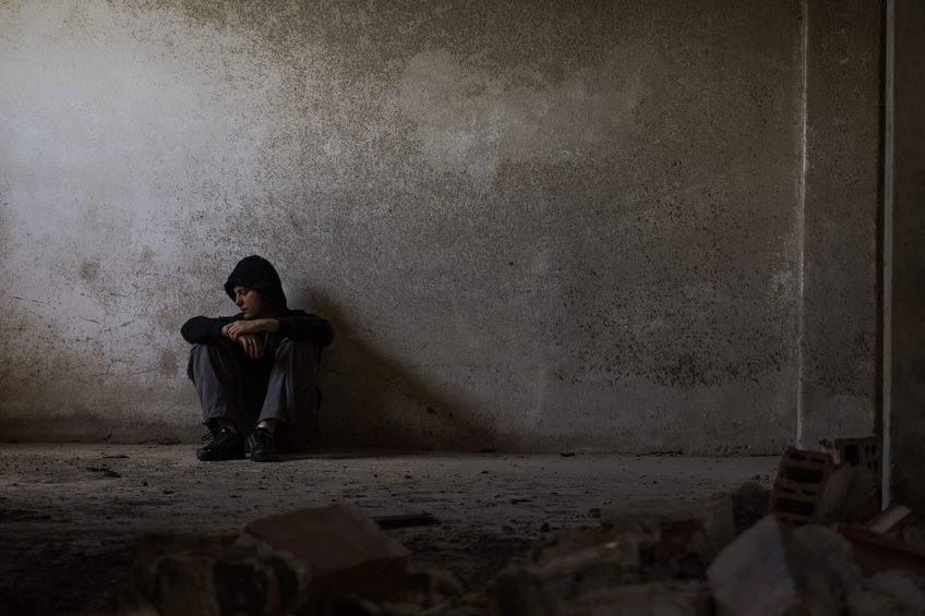 Man alone against a wall, grim, dark tone