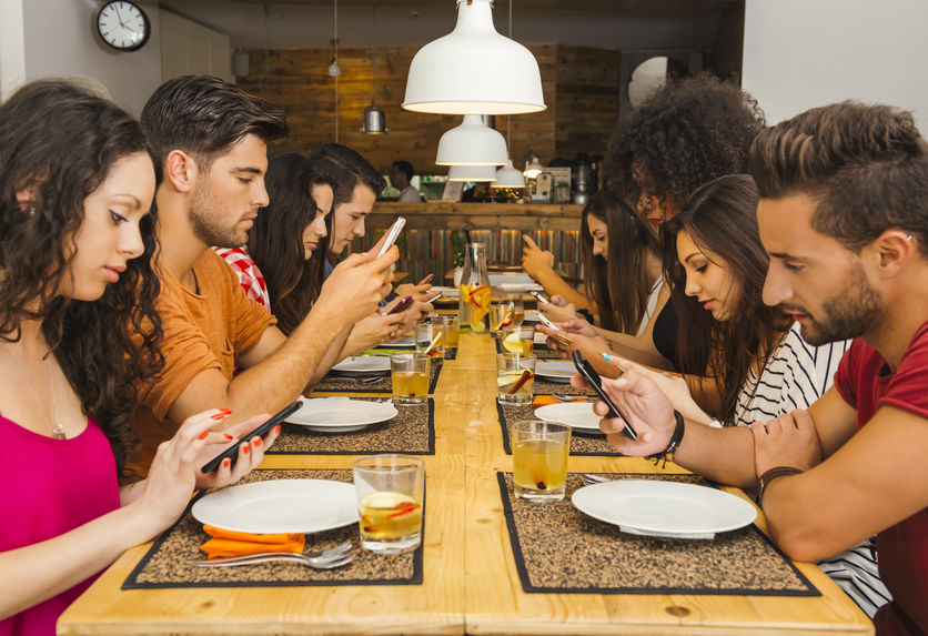 Group of friends at a restaurant with all people on the table occupied with cellphones