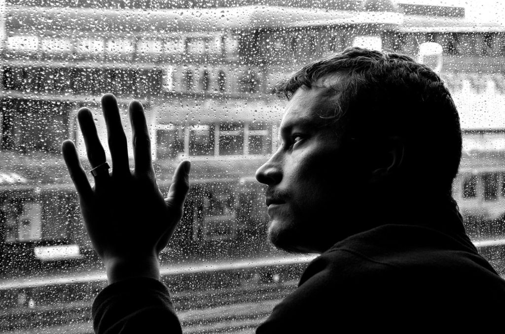 Safe but depressed, man looking out of a window