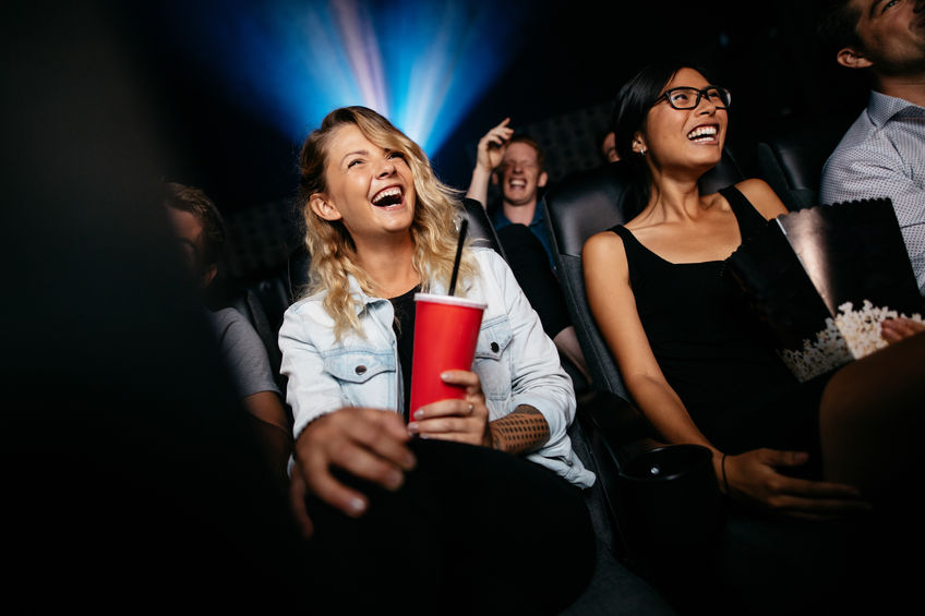 Young people laughing while watching film in movie theatre